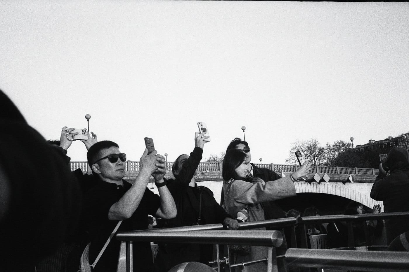 Black-and-white film photo: tourists taking photos on a boat